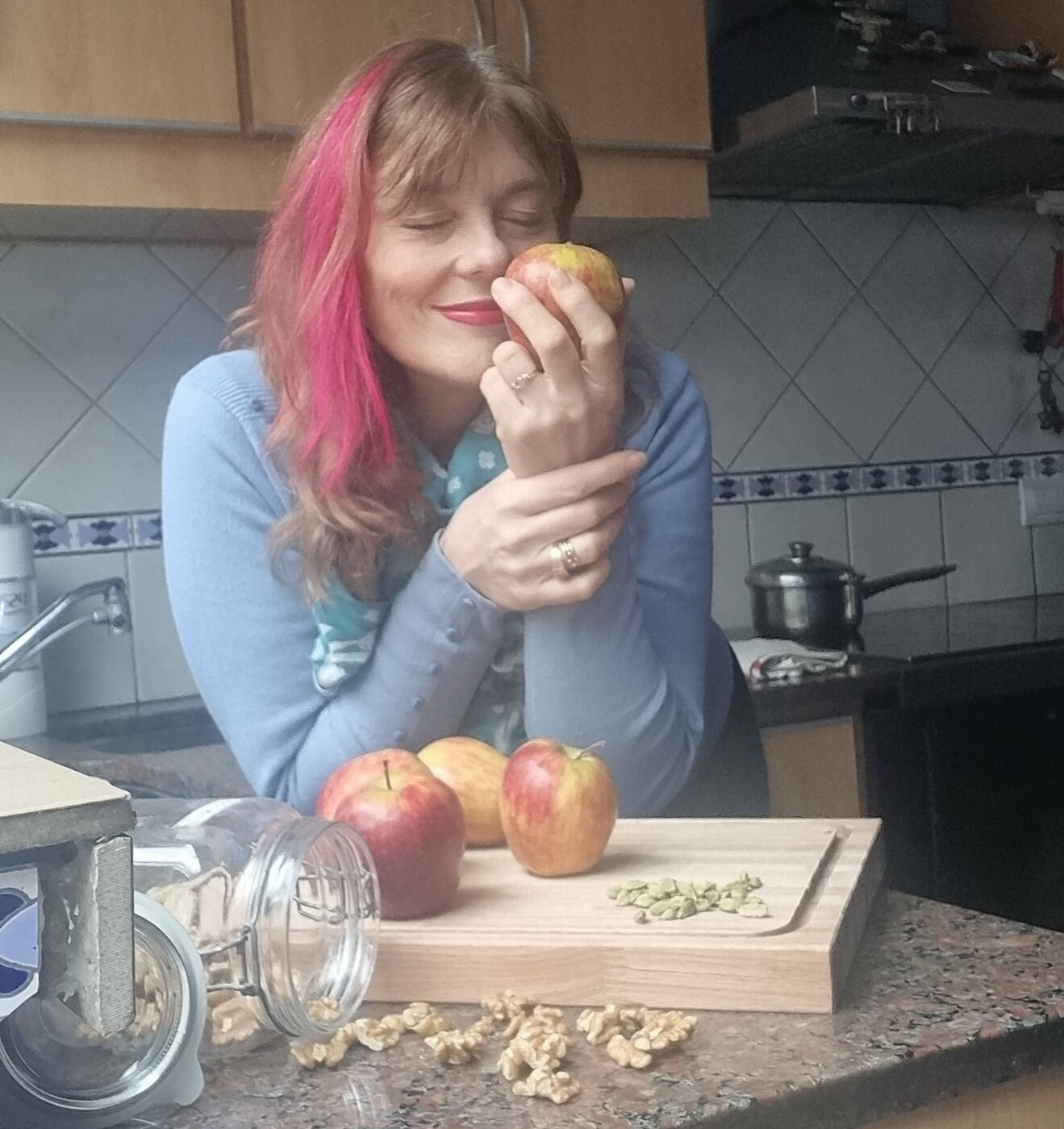 Sandra De Martin en su cocina, oliendo una manzana junto a nueces y cardamomo.